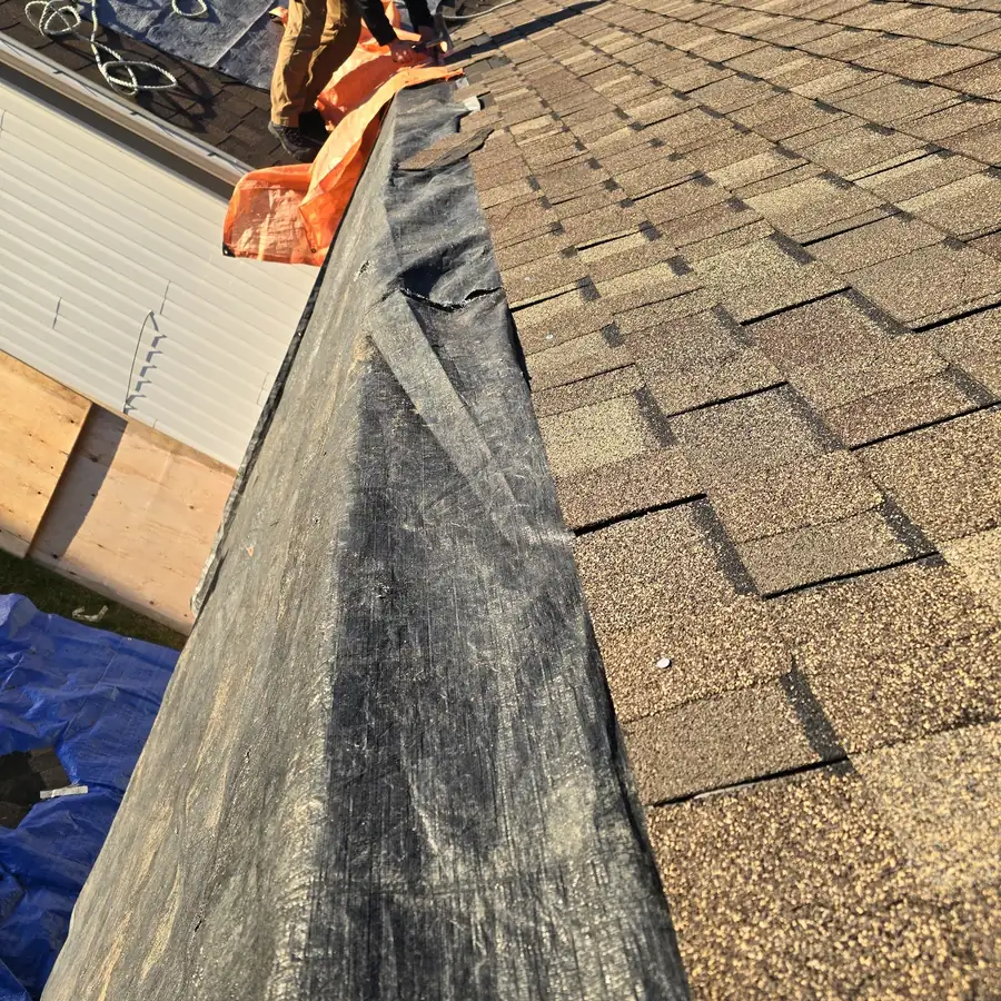 Raptor crew repairing an eave edge, waterproof membrane lapped over the metal with old shingles alongside