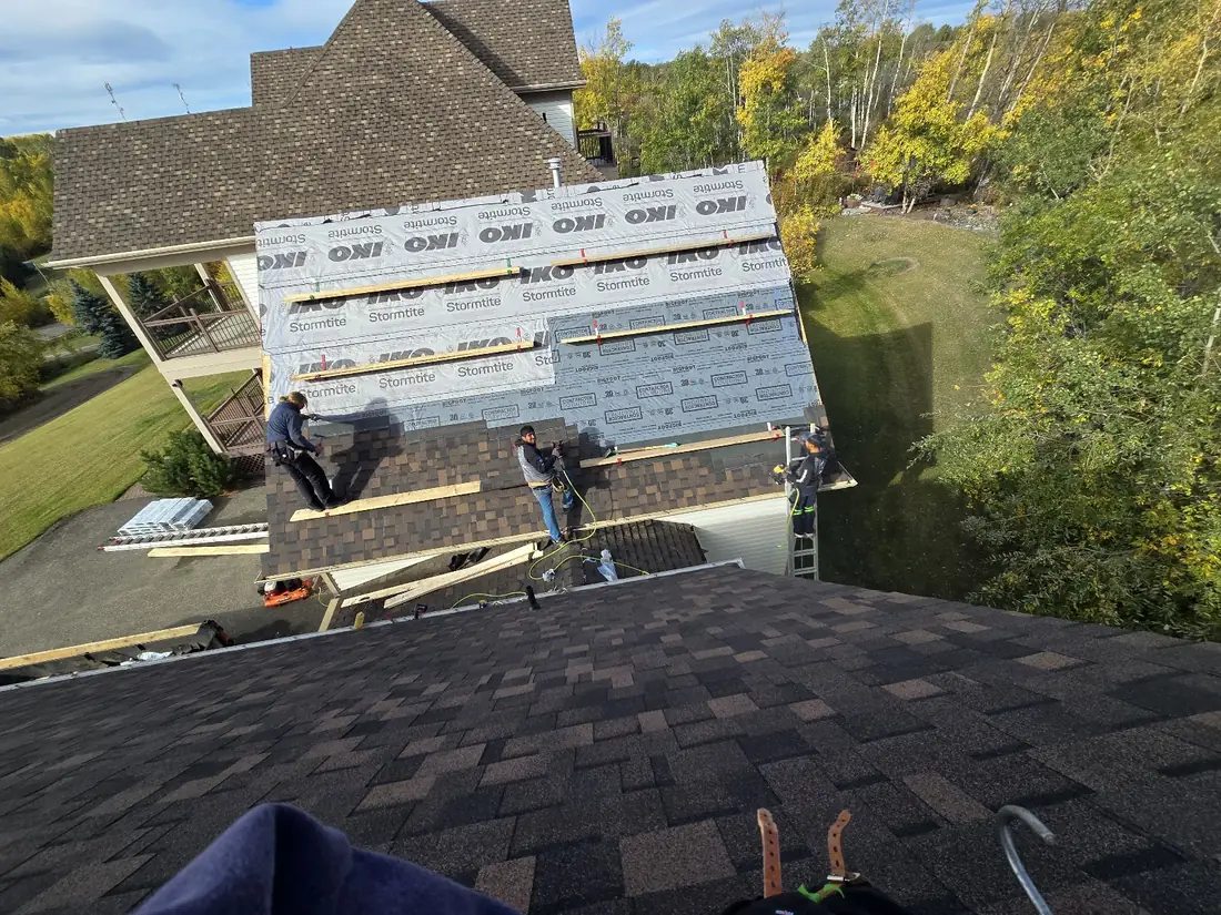 Raptor crew installing shingles course by course up a steep roof face, underlayment bands above