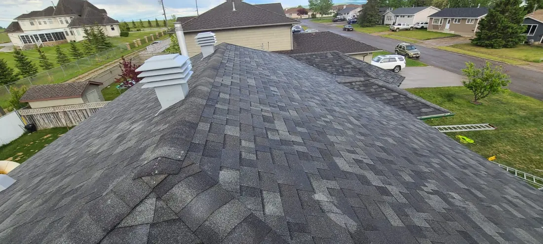 Completed shingle roof photographed from the ridge with new vents, Dawson Creek street below