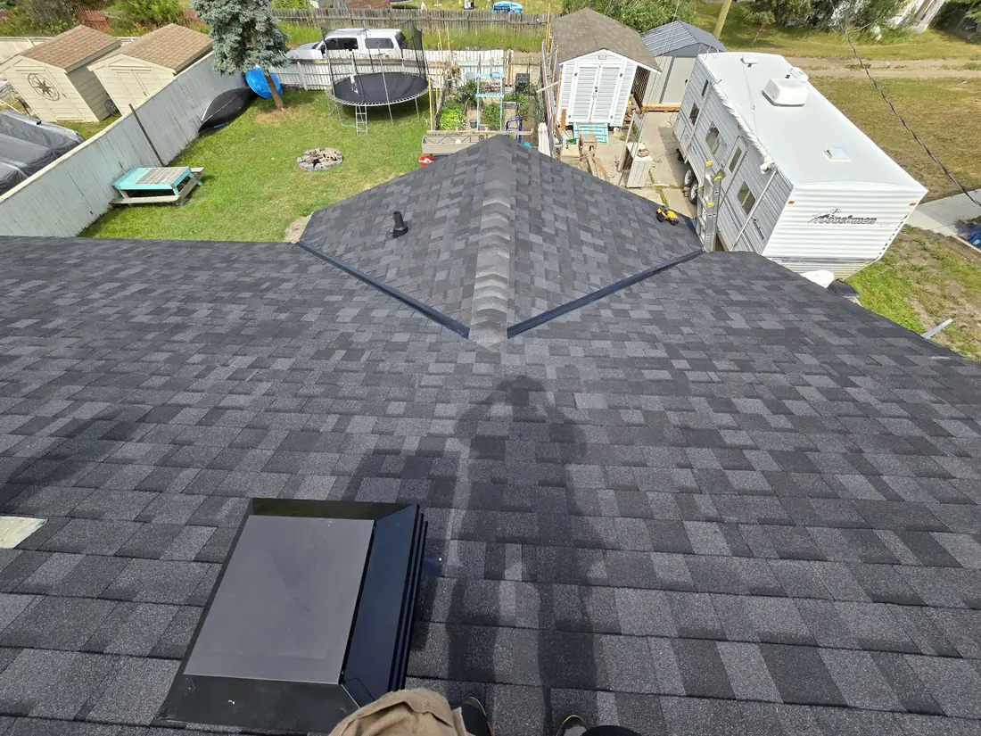 Completed dark asphalt shingle roof by Raptor Mountain Roofing with a low-profile skylight installed